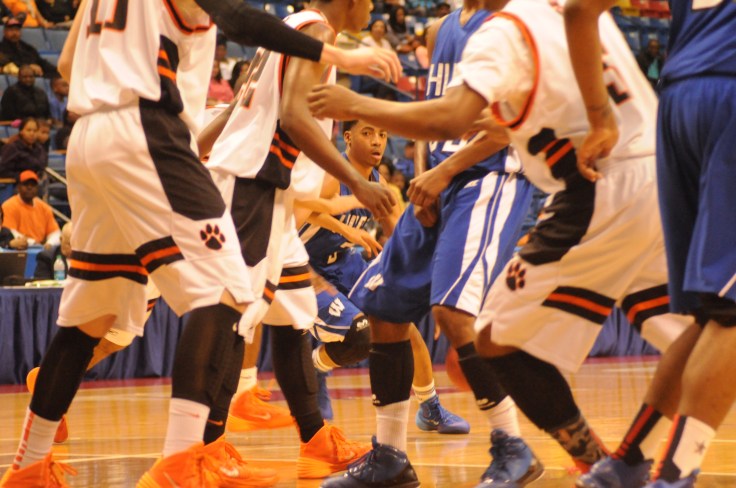 Basketball player eyes a spot to dribble to as others scurry about.